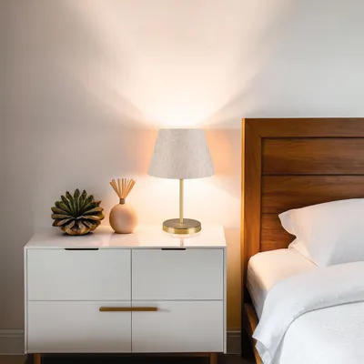 A bedside table with a lamp, a decorative plant, and a diffuser.