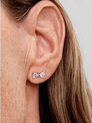 Close-up of a woman's ear wearing a bow-shaped earring.