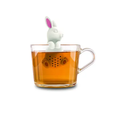 A white bunny-shaped tea infuser is partially submerged in a clear glass mug filled with amber-colored tea.