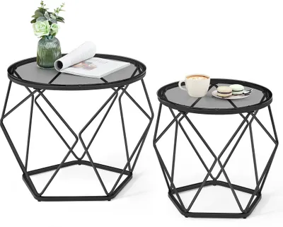 Two modern geometric side tables with glass tops, one with a vase of flowers and a magazine, the other with a cup of coffee and macarons.