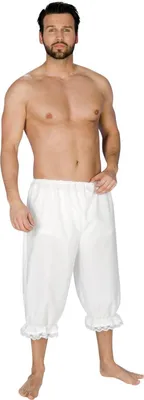 A man is posing in a studio setting wearing white knee-length pants.