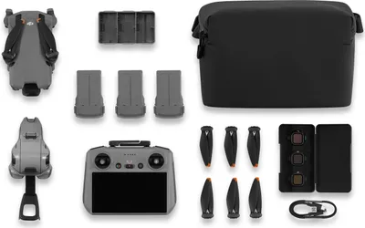 A flat lay of a drone and its accessories, including batteries, propellers, a controller, a carrying case, and filters, arranged on a white background.