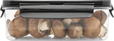 A clear plastic food storage container filled with mushrooms, with a black lid and locking mechanism.
