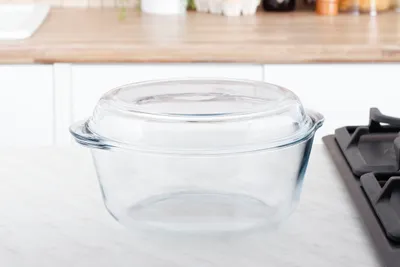 A clear glass casserole dish with a lid sits on a countertop in a kitchen setting.