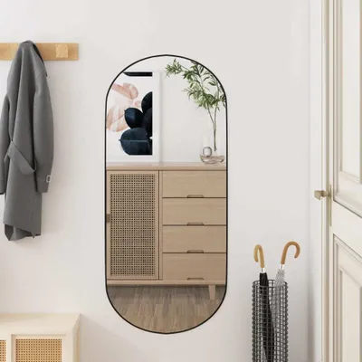 A hallway with a mirror reflecting a cabinet and artwork, a coat hanging on a rack, and an umbrella stand.