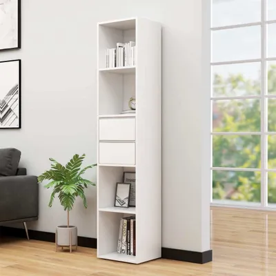 A white bookshelf filled with books and decorative items, placed next to a wall and a window with a view of trees.