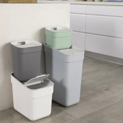Several trash cans are stacked and placed next to each other in a kitchen setting.