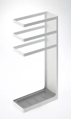 A white metal umbrella stand with a gray tray at the bottom, set against a white background.