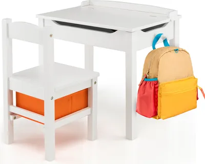 A white wooden children's desk and chair set with an orange storage bin under the seat and a colorful backpack hanging from the side of the desk.