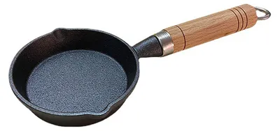 A cast iron mini frying pan with a wooden handle is shown against a white background.