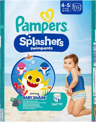 A child wearing swim pants on a beach with cartoon sharks.
