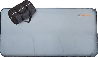 A folded baby mattress and a duffel bag are laid out on a light gray surface.