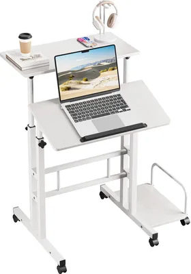 A white adjustable rolling laptop desk with a laptop, headphones, phone, and cup on it, against a white background.