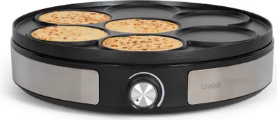 A crêpe maker with several crêpes being cooked.