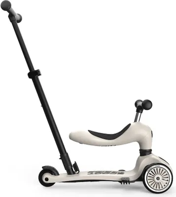 A white and black Scoot and Ride Highwaykick 1 Push and Go scooter with a seat attachment, shown against a white background.