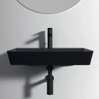 A black washbasin with a black faucet mounted on a white wall.