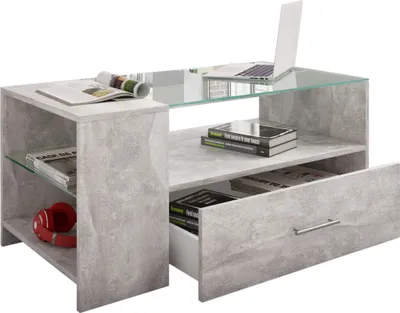 A modern coffee table with shelves, a drawer, and a glass top, featuring a minimalist design with a concrete-like finish.