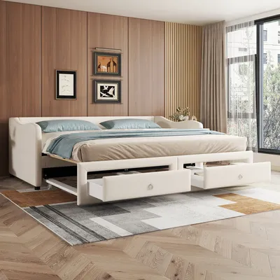 A beige upholstered sofa bed with two drawers open, set up in a bedroom with wood-paneled walls and a large window.