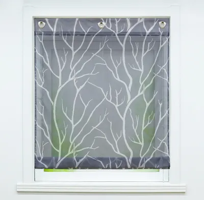 A close-up view of a window with a grey roller blind featuring a white tree branch pattern.