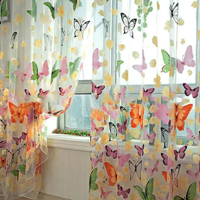 A sheer curtain with a butterfly pattern hanging in front of a window.