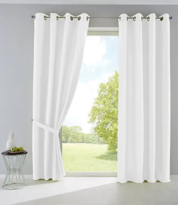 A room with a large window covered by white curtains, showing a green outdoor landscape.