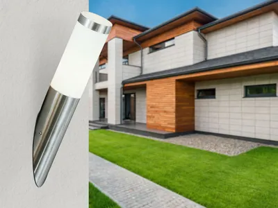 A modern house with a well-maintained lawn and a pathway leading to the entrance. A wall-mounted outdoor light is shown in the foreground.