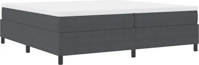 A dark gray boxspring bed with a white mattress on top, shown from a side-angle against a white background.
