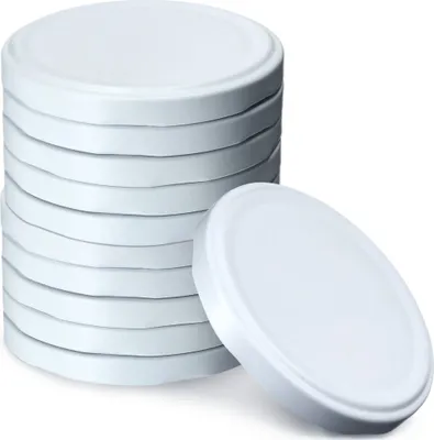 A stack of white metal jar lids with one lid placed in front of the stack.