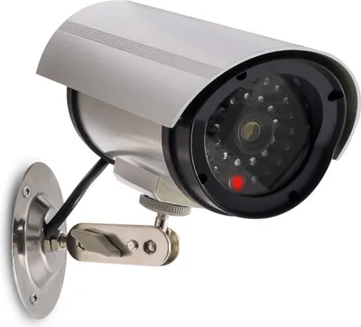 A security camera dummy with a red LED light is mounted on a wall.