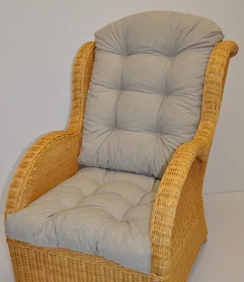 A close-up view of a wicker armchair with gray cushions.