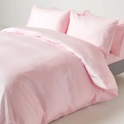 A pink striped duvet cover and pillowcases are neatly arranged on a bed.