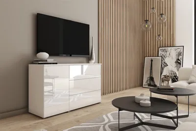 A modern living room with a TV on a white high-gloss dresser, coffee tables, and artwork.