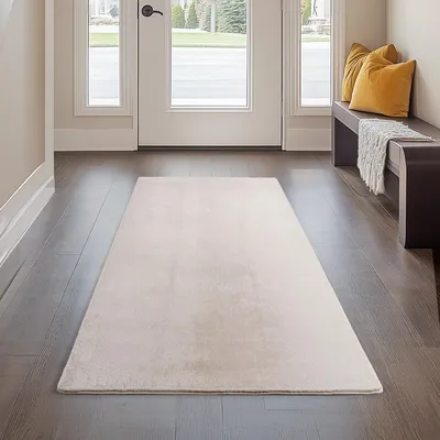 A hallway with a rug, bench, and pillows.