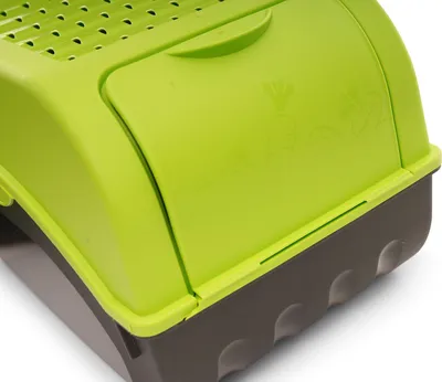 A close-up view of a green and gray storage container, possibly for vegetables.