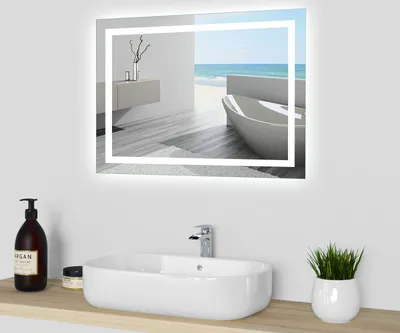 A modern bathroom sink with a mirror above it, reflecting a serene bathroom scene with a bathtub and ocean view.