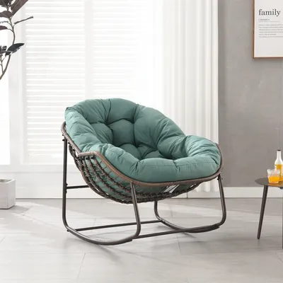 A green papasan chair with a steel frame is shown in a well-lit room with a window and a framed picture on the wall.