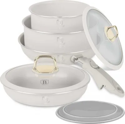 A set of white cookware with gold accents, including pots, a pan, a detachable handle, and lids, arranged on a white background.