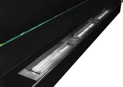 A close-up shot of a black ethanol fireplace with silver burners, set against a white background.