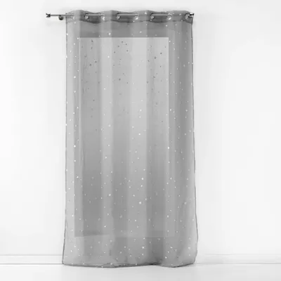 A sheer gray curtain with silver star-like speckles hangs against a white wall.