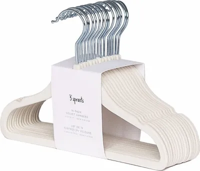 A stack of cream-colored velvet hangers with silver hooks, neatly arranged and held together by a cardboard band.