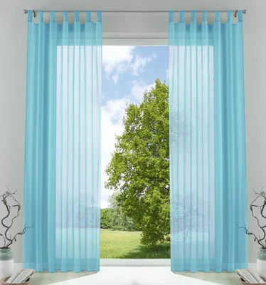 A pair of light blue sheer curtains hanging in front of a window with a view of a large green tree and a blue sky.