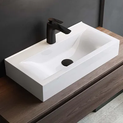 A white rectangular sink with a black faucet is placed on a wooden vanity.