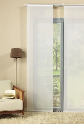 A living room scene with a sofa, lamp, and sliding panel curtains.