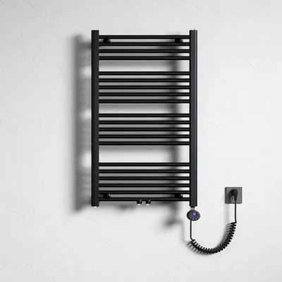 A black electric towel radiator mounted on a textured white wall, with a coiled power cord connected to a wall socket.