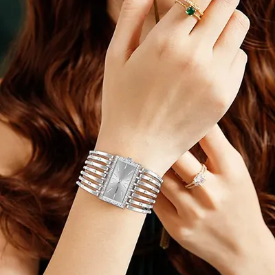 A close-up shot of a woman's wrist wearing a silver watch and rings.