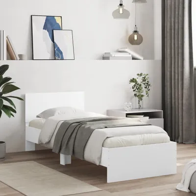 A white bed frame with a headboard and bedding is shown in a bedroom setting.