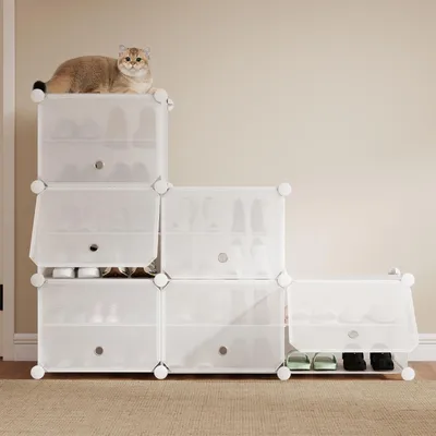 A white modular shoe rack with a cat on top, filled with shoes.