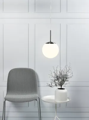 A modern interior scene with a pendant light, a chair, and a small table with a plant.