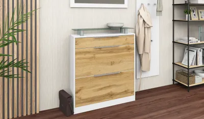 A shoe cabinet with a wood-effect front and white frame, placed in a hallway next to a plant and a coat rack.