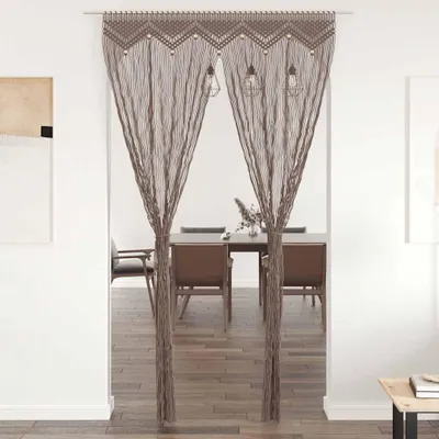 A macrame curtain hanging in a doorway, with a dining room visible in the background.
